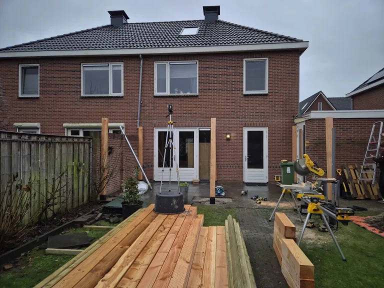 Begin van een houten overkapping: palen en balken in de achtertuin