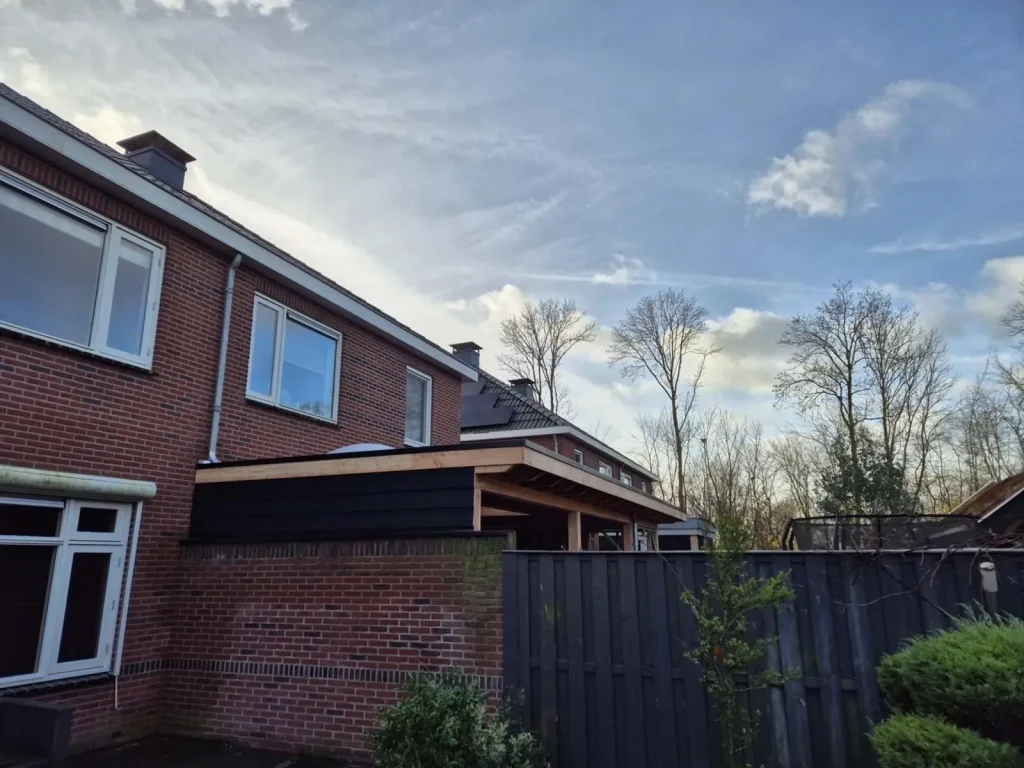Overkapping met plat dak langs de achtergevel van een woning